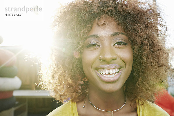 Sonne strahlt auf das Gesicht einer lächelnden schwarzen Frau