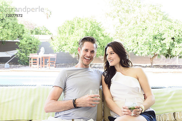 Lächelndes kaukasisches Paar entspannt sich mit kalten Getränken im Freien