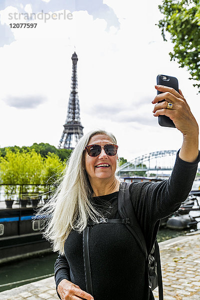 Kaukasische Frau posiert für Handy-Selfie in der Nähe des Eiffelturms