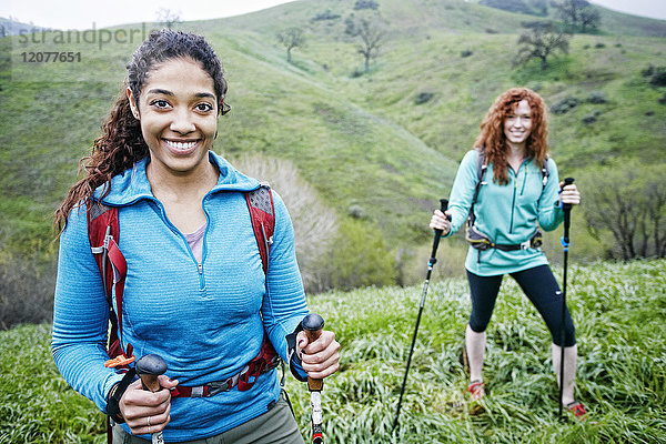 Porträt einer lächelnden Frau beim Wandern mit Wanderstöcken