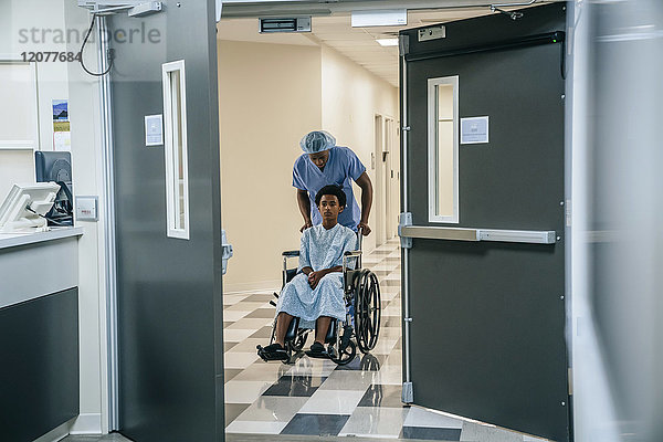 Schwarze Krankenschwester schiebt Jungen im Rollstuhl