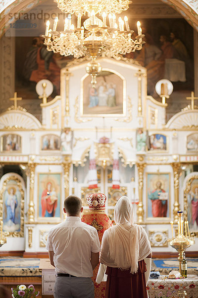 Ehepaar und Priester in der Kirche stehend