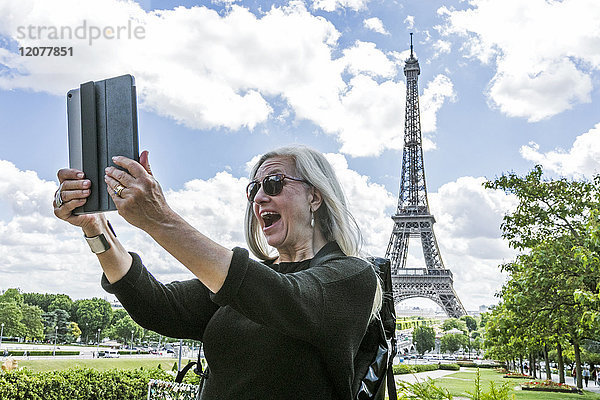 Kaukasische Frau posiert für digitales Tablet-Selfie in der Nähe des Eiffelturms