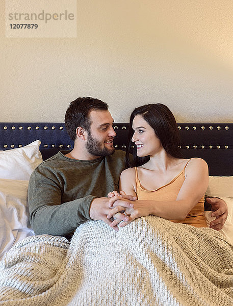 Kaukasisches Paar hält Hände im Bett