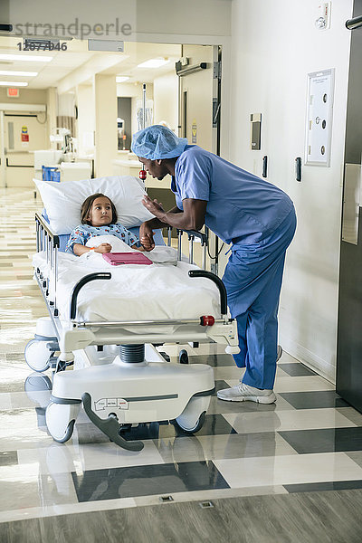 Krankenschwester spricht mit einem Mädchen auf einer Krankenhausliege