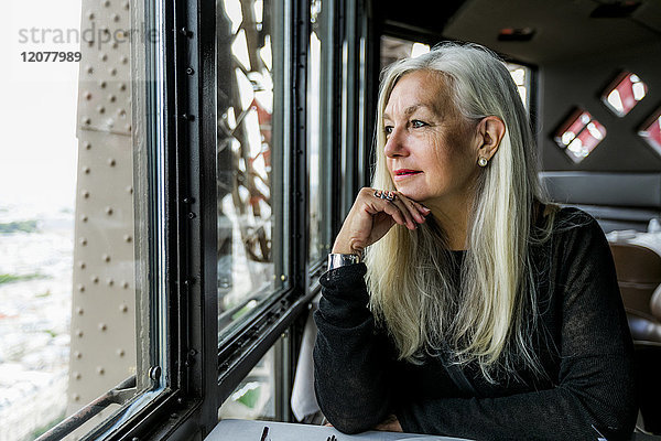 Kaukasische Frau bewundert die Aussicht aus dem Fenster eines Restaurants