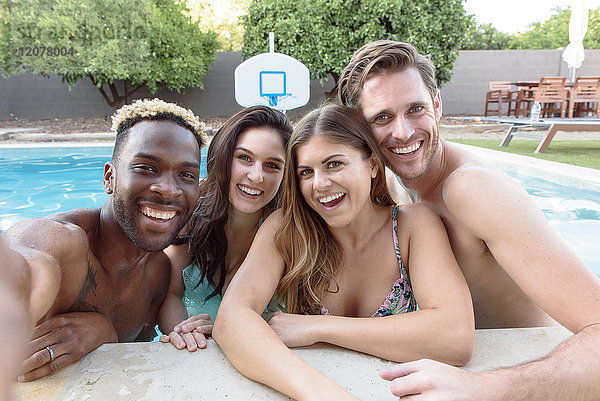 Lächelnde Freunde im Schwimmbad posieren für ein Selfie