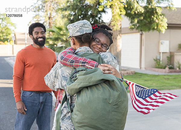 Mann beobachtet schwarze Soldatin  die ihre Tochter umarmt