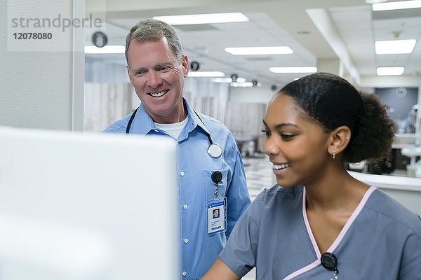 Lächelnder Arzt und Krankenschwester am Computer