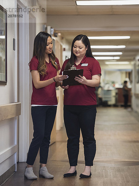 Krankenschwestern lesen Klemmbrett im Krankenhauskorridor