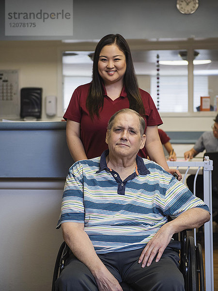 Porträt einer lächelnden Krankenschwester und eines Patienten im Rollstuhl