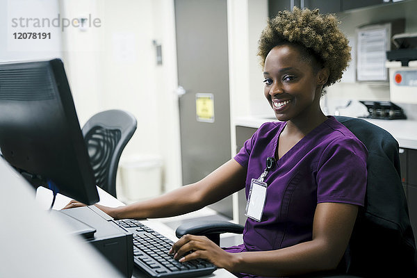 Porträt einer lächelnden schwarzen Krankenschwester am Computer