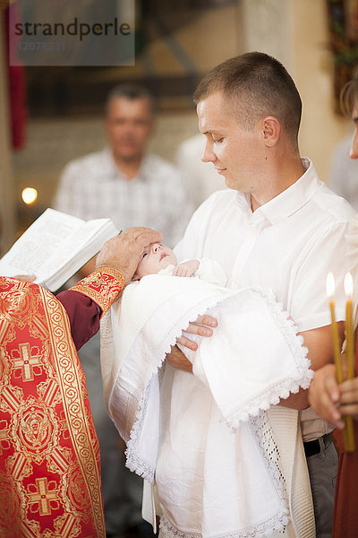 Priester segnet kleinen Jungen in der Kirche