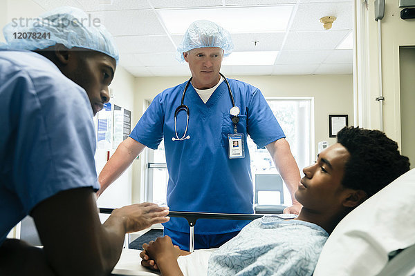Krankenschwestern sprechen mit einem Jungen im Krankenhausbett