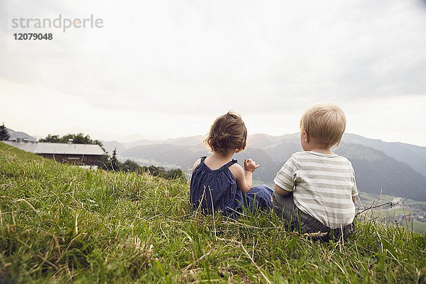 Österreich  Tirol  Rückansicht des kleinen Mädchens und Jungen auf der Alm mit Blick auf die Aussicht