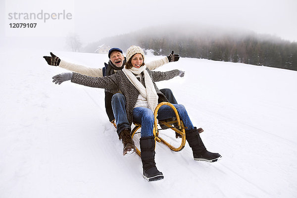 Seniorenpaar beim Schlittenwandern im Schnee