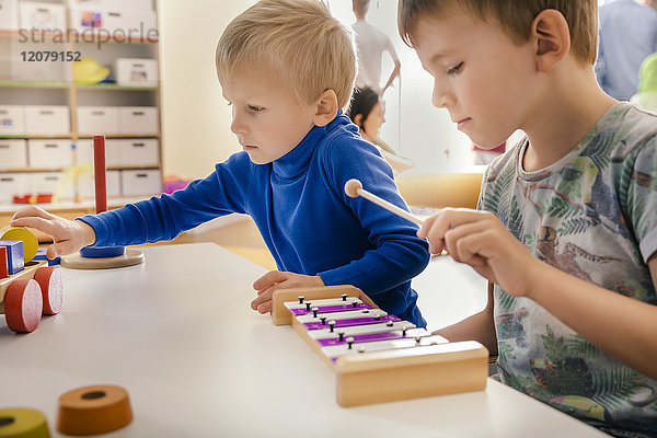 Zwei Jungen spielen mit Musikinstrumenten und Spielzeug im Kindergarten