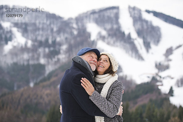 Fröhliches Seniorenpaar von Angesicht zu Angesicht in der Winterlandschaft nach oben