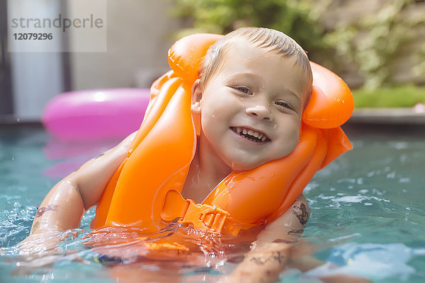 Portrait eines glücklichen Jungen mit Schwimmweste im Schwimmbad