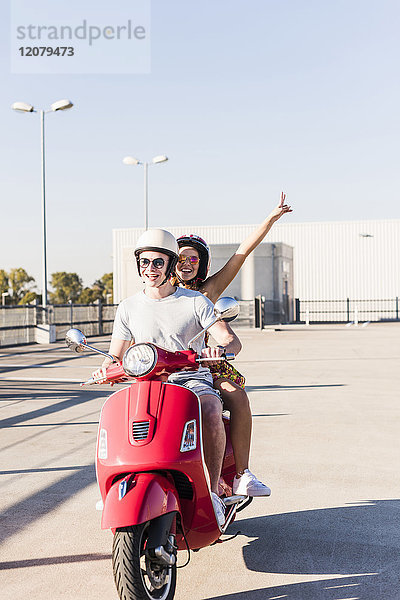 Sorgenfreies junges Paar auf dem Motorroller auf der Parkebene