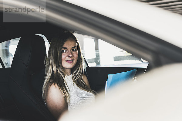 Lächelnde junge Frau mit Dokumenten im Auto