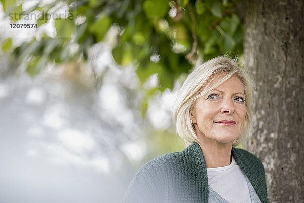 Porträt der zufriedenen Seniorin in der Natur