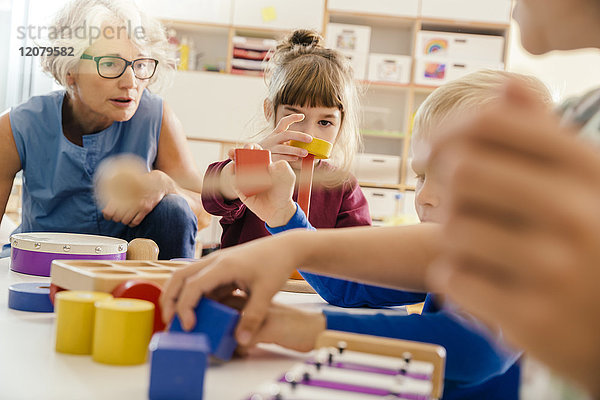 Kinder und Lehrer beim Spielen mit Musikinstrumenten und Spielzeug im Kindergarten
