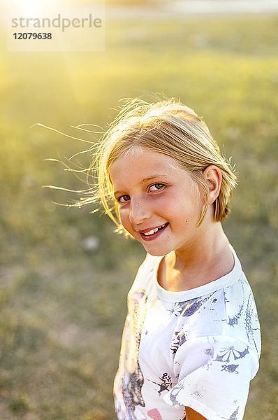 Porträt eines lächelnden blonden Mädchens im Gegenlicht