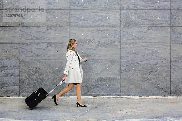 Geschäftsfrau mit Koffer im Trenchcoat