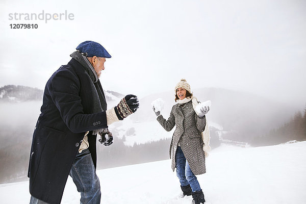 Seniorenpaar bei einer Schneeballschlacht im Schnee