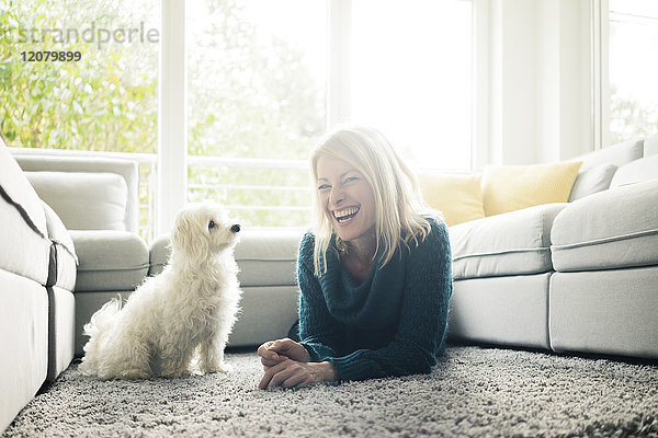 Glückliche Frau mit Hund im Wohnzimmer