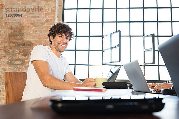 Glückliche junge Unternehmerin  die im Kooperationsraum mit dem Laptop arbeitet.