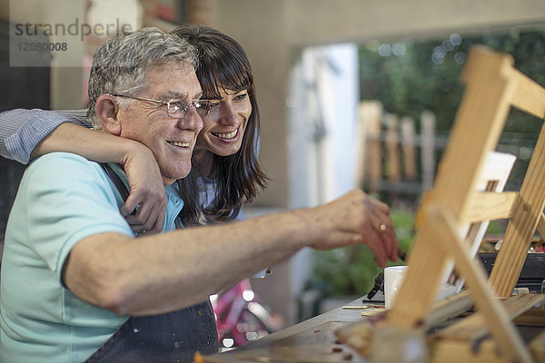 Lächelnde Frau umarmt die Malerei des älteren Mannes