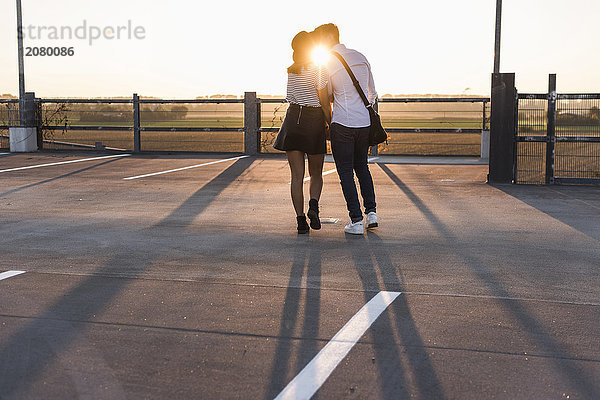 Junges Paar  das sich bei Sonnenuntergang auf der Parkebene küsst.