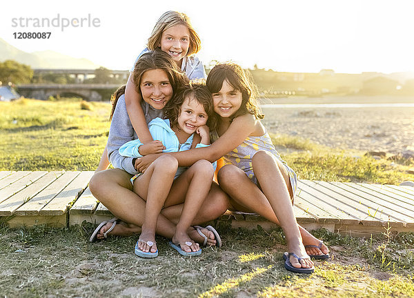 Gruppenbild von vier Mädchen  die im Sommer auf der Strandpromenade sitzen
