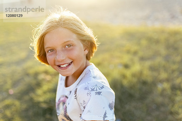 Porträt eines glücklichen blonden Mädchens im Gegenlicht