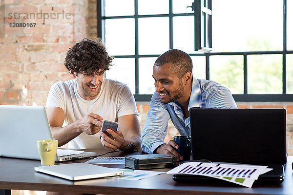 Zwei junge Geschäftsleute arbeiten zusammen in einem Arbeitsraum mit Laptops.