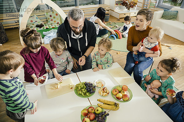 Gruppe von Kindern und Lehrern  die im Kindergarten Obst zubereiten