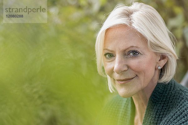 Porträt einer lächelnden Seniorin in der Natur