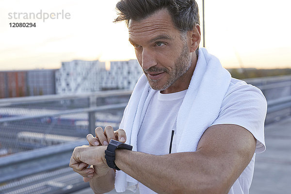 Sportler in der Stadt mit Smartwatch und Handtuch