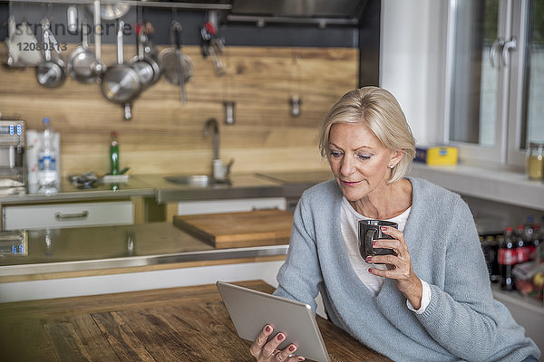 Seniorin mit Tablette in der Küche