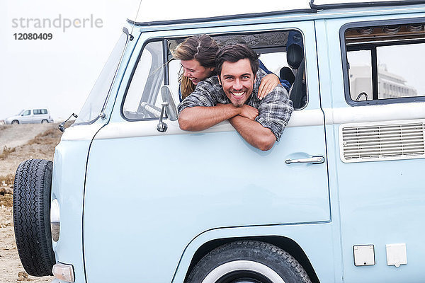 Spanien  Teneriffa  Porträt eines lachenden Mannes und seiner Freundin  die sich aus dem Autofenster eines Wohnmobils lehnen.