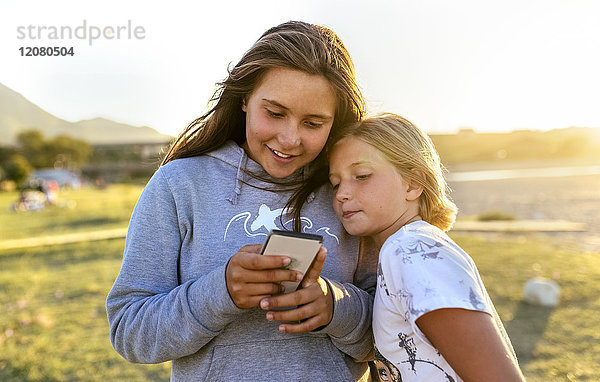 Zwei Mädchen  die das Handy im Freien anschauen