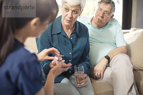 Krankenschwester  die der älteren Frau zu Hause Medikamente verabreicht.