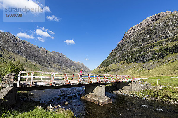 Großbritannien  Schottland  Schottische Highlands  Glencoe  Loch Achtriochtan  weibliche Touristen  die über die Brücke laufen