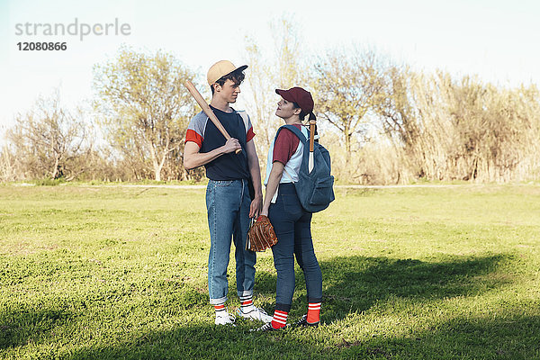 Junges Paar mit Baseballausrüstung im Park