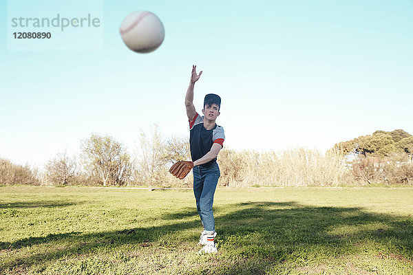 Junger Mann wirft einen Baseball im Park