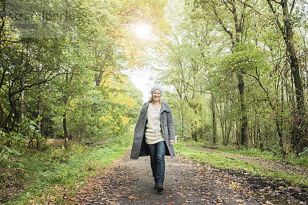 Porträt einer glücklichen Frau  die im Herbst im Wald spazieren geht.