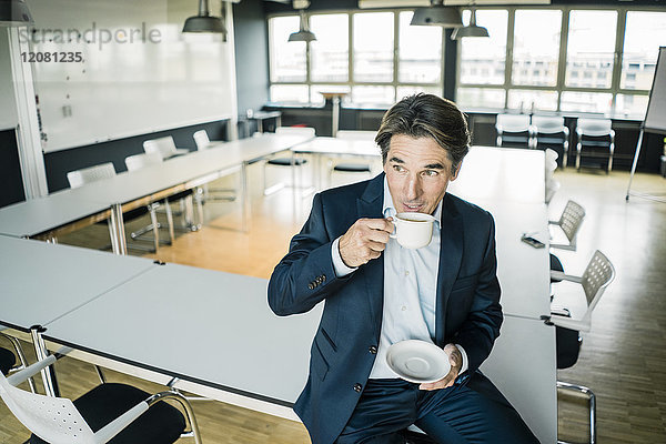 Geschäftsmann mit Tasse Kaffee auf dem Tisch im Besprechungsraum eines Büros