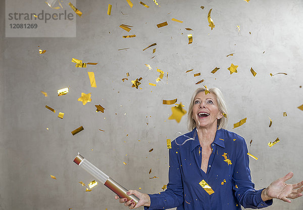 Porträt einer verblüfften Seniorin beim Betrachten von goldenem Konfetti